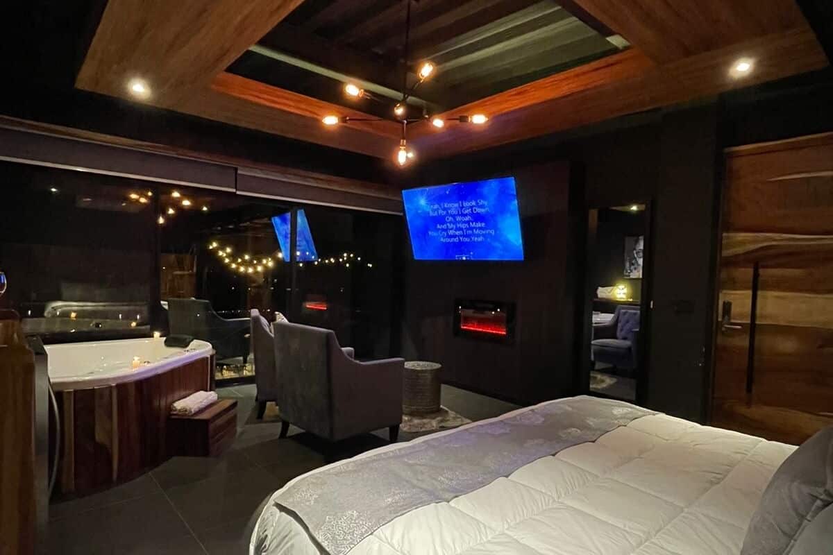 A modern bedroom with a large bed, a TV, and a small seating area with a chair and a table.