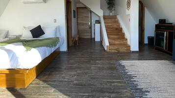 Une chambre spacieuse avec un grand lit, un escalier en bois et une vue sur le salon.