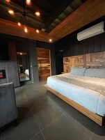 Un dormitorio moderno con una cama grande, cabecero de madera y un equipo de aire acondicionado.