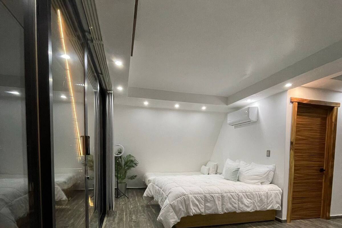 A modern bedroom with a large bed, a wooden floor, and a sliding glass door.