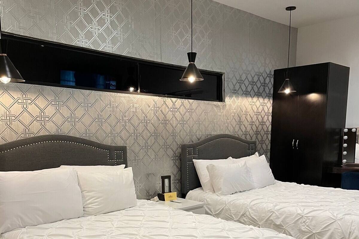 A hotel room with two beds, a wardrobe, and a vanity with lights.
