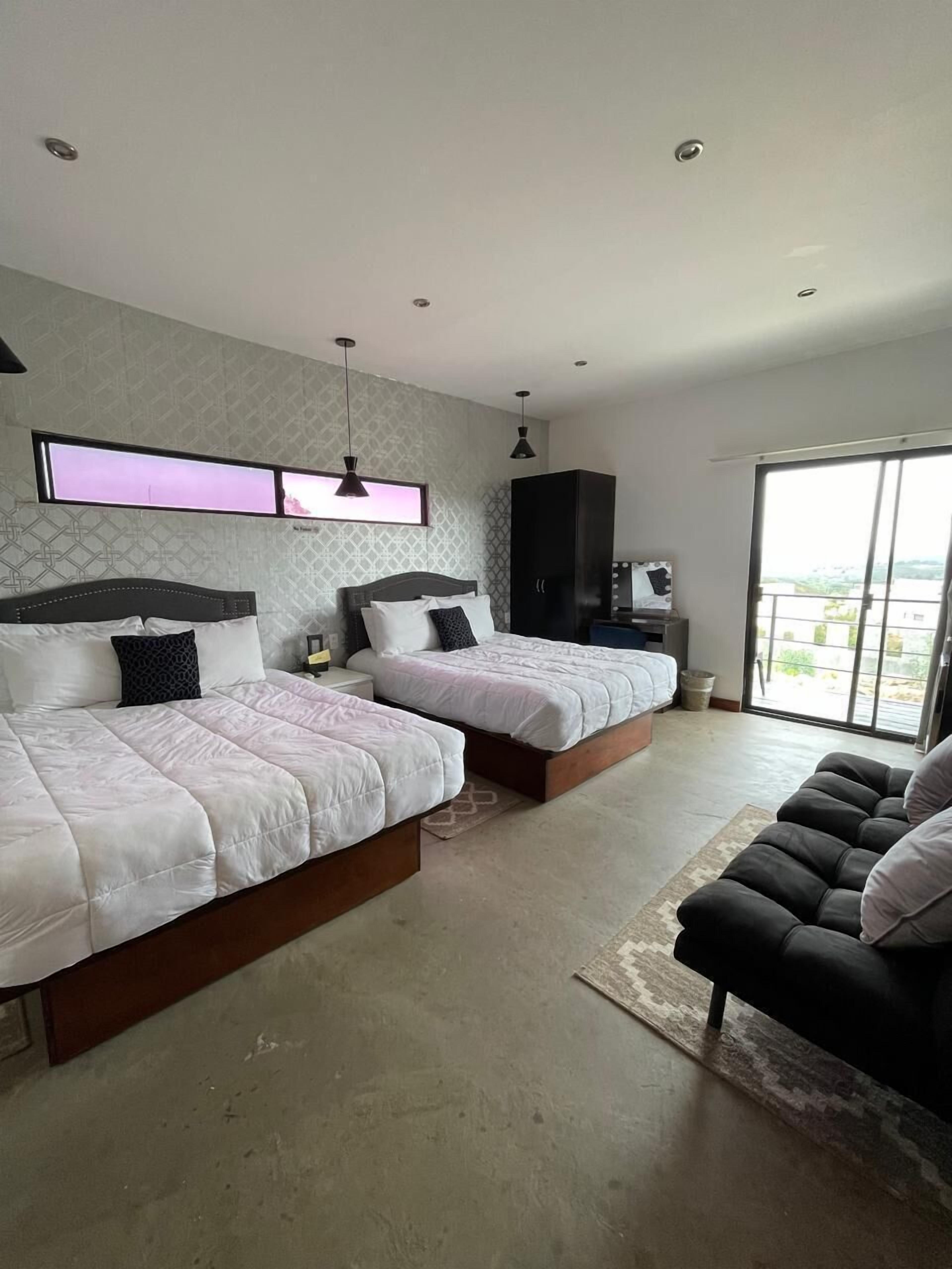 Een moderne slaapkamer met twee bedden, een groot raam en uitzicht op de stad.