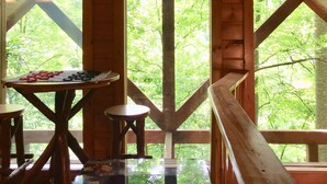 Una cabaña de madera con un ventanal grande y una mesa con un juego.