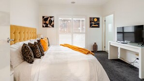 A hotel room with a bed, a desk, a television, and artwork on the walls. - Relax & Unwind with Private Hot Tub in Rosebud (Rosebud)