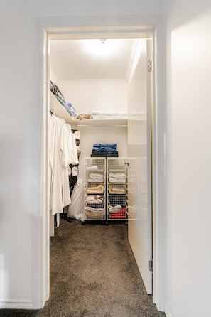 A walk-in closet with hanging clothes, a folded clothes rack, and a shoe rack. - Relax & Unwind with Private Hot Tub in Rosebud (Rosebud)