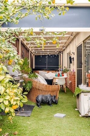 A covered outdoor seating area with a grill, a dining table, and a sofa. - Relax & Unwind with Private Hot Tub in Rosebud (Rosebud)