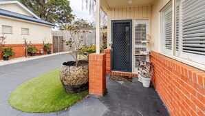 A residential property with a paved driveway, a brick entrance, a large planter with a tree, and a garage door. - Relax & Unwind with Private Hot Tub in Rosebud (Rosebud)
