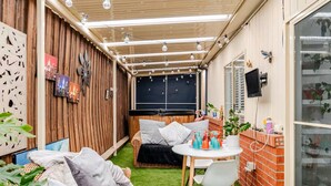 A cozy outdoor living area with a sofa, a dining table, and a TV screen. - Relax & Unwind with Private Hot Tub in Rosebud (Rosebud)