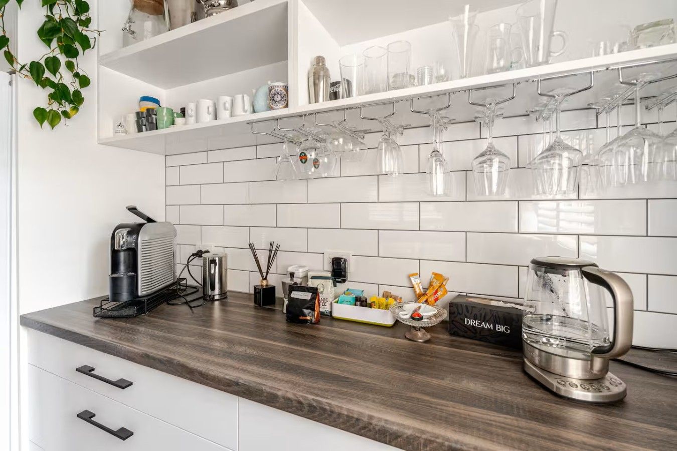Een keuken met witte kasten, een houten aanrecht en een koffieapparaat.