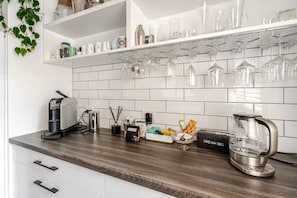 A kitchen with white cabinets, a wooden countertop, and a coffee machine.