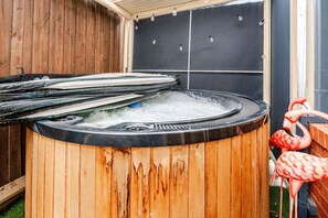 Un jacuzzi con revestimiento de madera, rodeado por una valla de madera y un muro de ladrillo.
