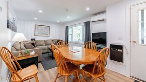 A room with a wooden dining table, four chairs, a sofa, a lamp, a television, and a map on the wall. - Lakefront Muskoka Retreat 4 Bedroom Cottage  (MacTier)