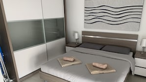 Ein modernes Schlafzimmer mit einem Bett, zwei Nachttischen, einem Wandbild und einem Kleiderschrank.