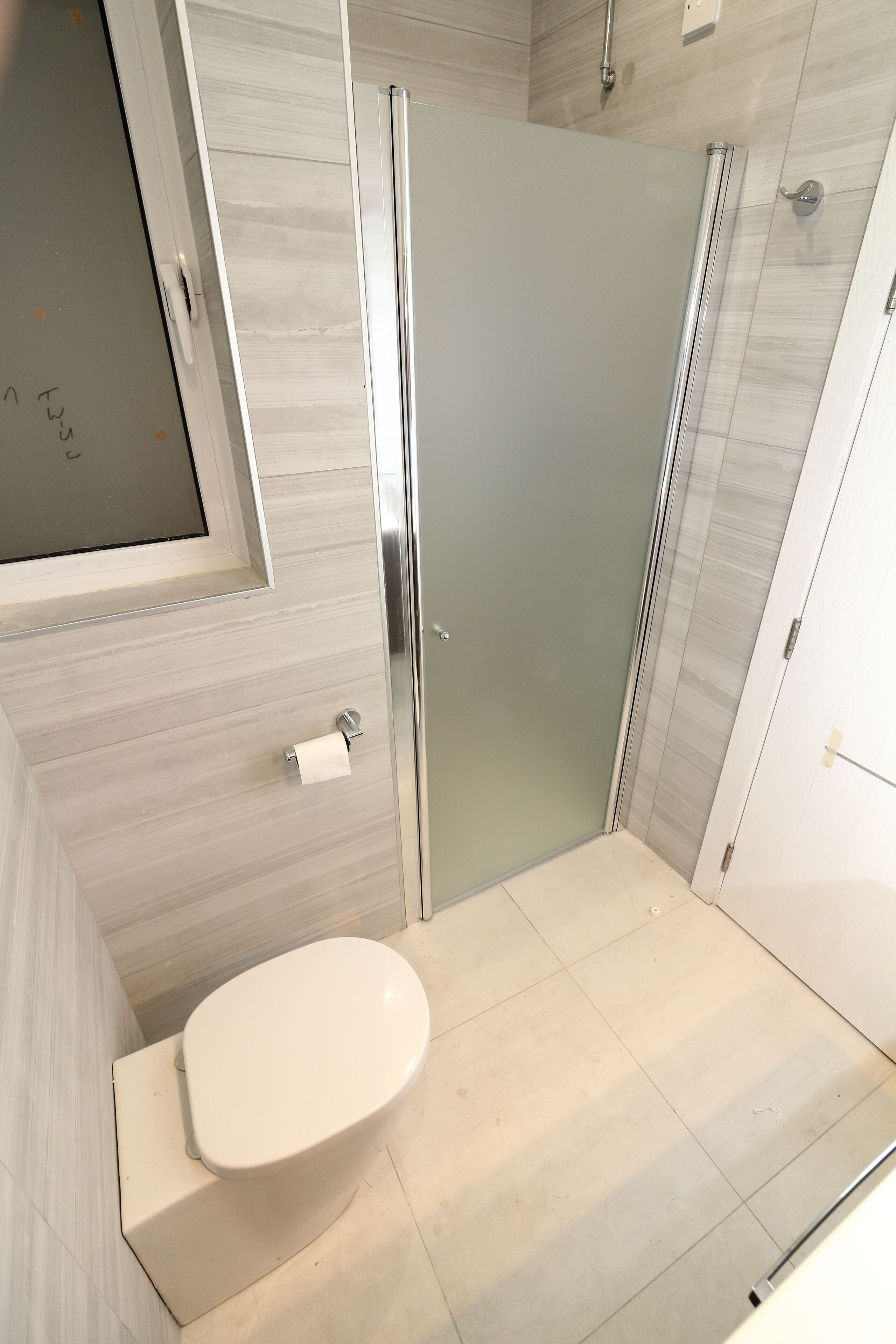 Ein modernes Badezimmer mit Toilette, einer Glasdusche und einer weißen Tür.