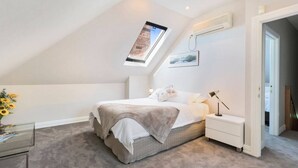 A bedroom with a skylight, a bed, a bedside table, and a nightstand. - Hampden Manor A Refined Battery Point Period Home (Battery Point)