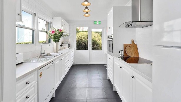 A modern kitchen with white cabinetry, a built-in oven, a microwave, and a wooden cutting board. - Hampden Manor A Refined Battery Point Period Home (Battery Point)