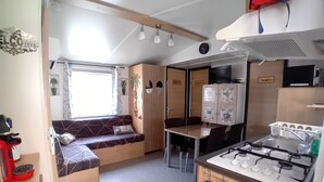 A compact RV kitchen with a stove, sink, and seating area.