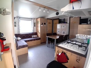 Eine kleine Küchenzeile in einem Wohnmobil mit Herd, Spüle und einer Sitzgruppe.