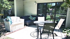 Une terrasse extérieure avec une table ronde et des chaises, un canapé et un espace salon abrité.