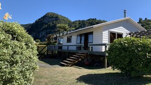Une maison blanche avec une terrasse en bois et une vue sur les montagnes en arrière-plan.