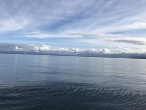Una masa de agua tranquila con una cadena montañosa y nubes a lo lejos.