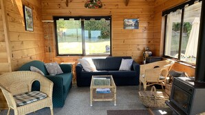 L’intérieur chaleureux d’un chalet avec un canapé, deux fauteuils en osier, une petite table et un poêle à bois.