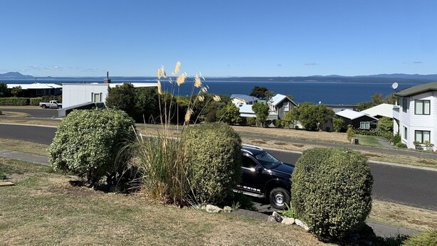 Un quartier résidentiel avec des maisons, une route et une vue sur la mer.