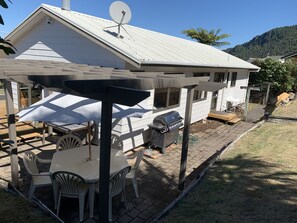 Un patio con mesa y sillas, una parrilla y un espacio de estar techado.