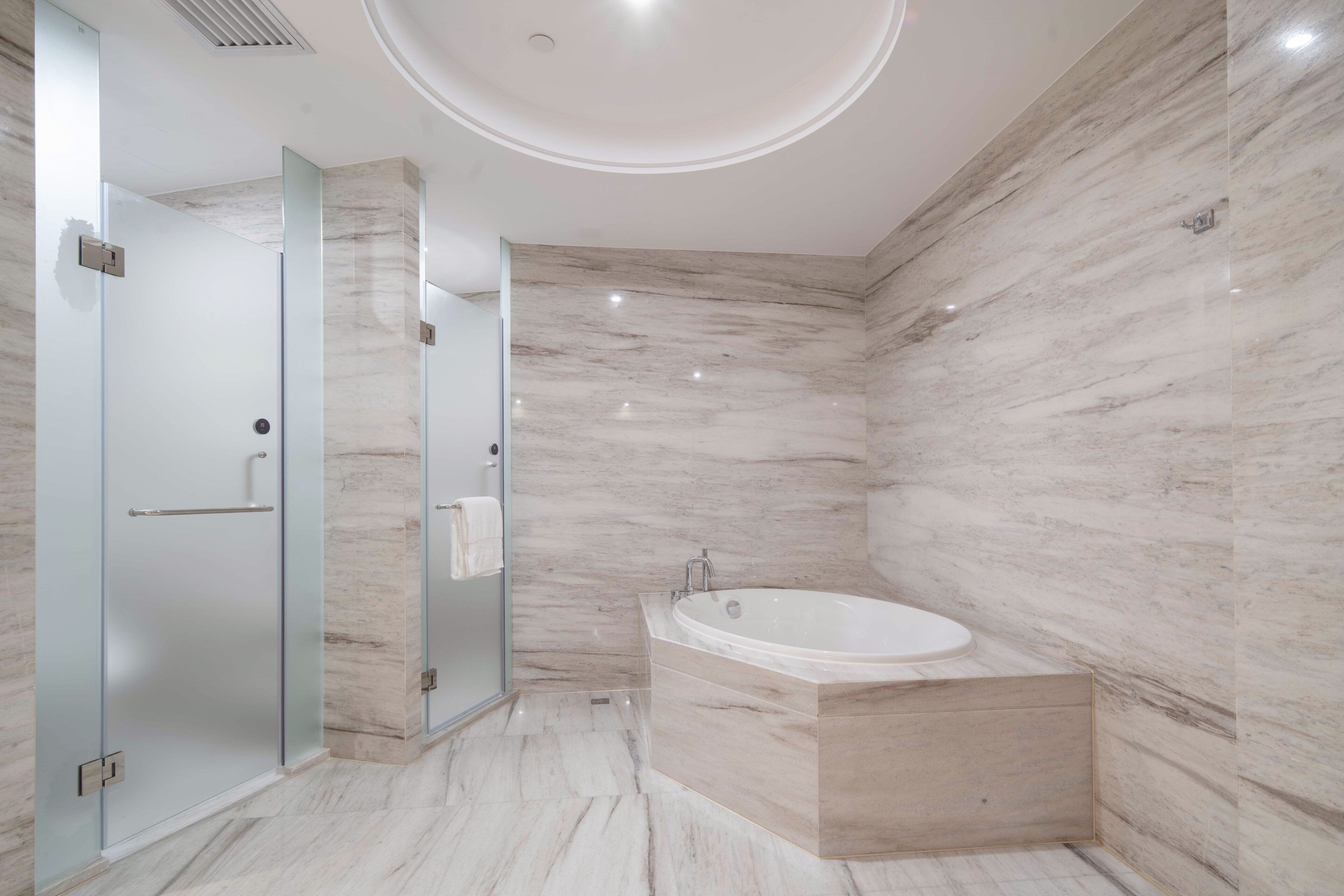 Un baño moderno con cabina de ducha de vidrio, una bañera independiente y paredes de mármol.