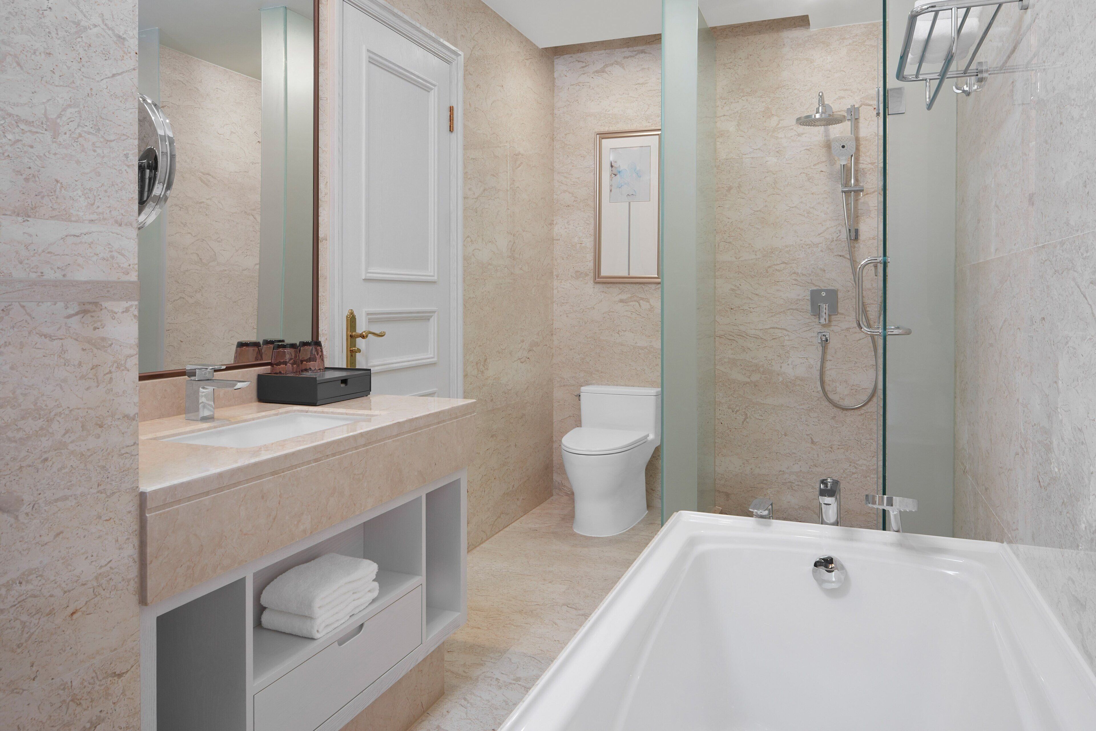 A modern bathroom with a large bathtub, a sink with a vanity, a toilet, and a glass-enclosed shower area.