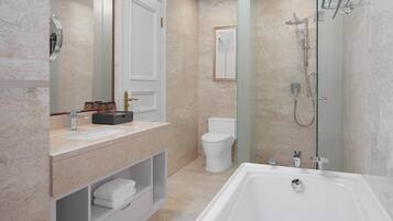 A modern bathroom with a large bathtub, a sink with a vanity, a toilet, and a glass-enclosed shower area.