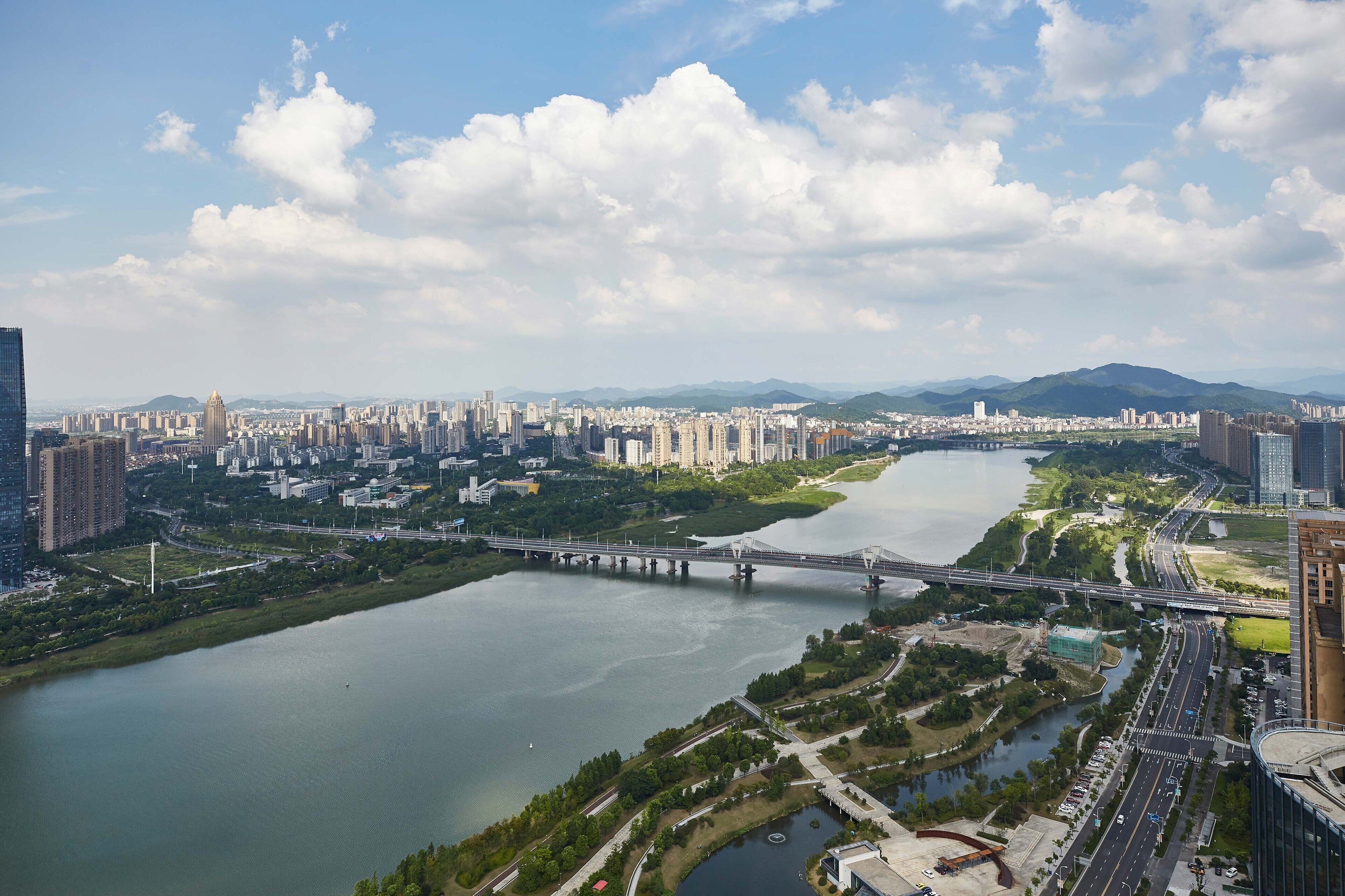 Paisagem urbana com um rio, uma ponte e edifícios altos.