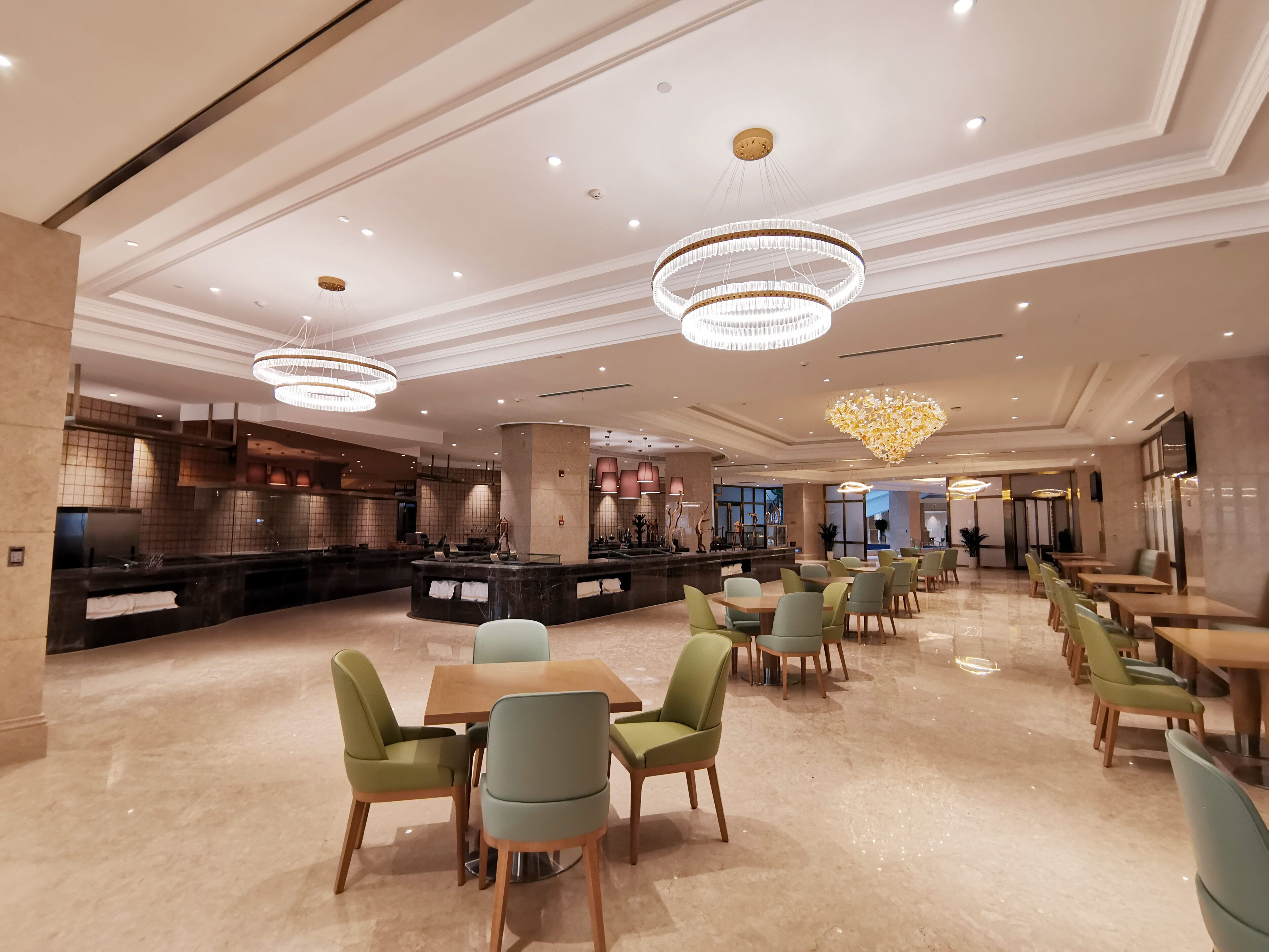 Un vestíbulo de hotel espacioso con una zona de bar central, varios arreglos de asientos y elegantes candelabros.