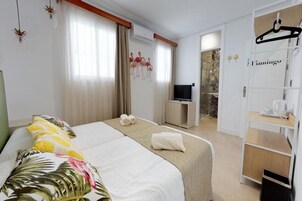 Habitación de hotel con cama, televisión, armario y baño.