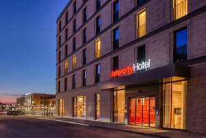 Un hotel moderno con un llamativo letrero de "Intercity Hotel", amplias ventanas y fachada de ladrillo.