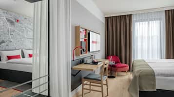 Una habitación de hotel moderna con una cama, un escritorio con una silla, un televisor y un mapa en la pared.