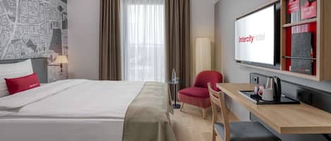 Una habitación de hotel con cama, escritorio, silla, televisión y un mapa en la pared.
