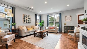 A spacious living room with a fireplace, two sofas, a coffee table, and a large window with curtains.