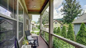 A covered porch with a view of a residential neighborhood, including houses and trees.