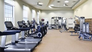 Un gimnasio con cintas de correr, máquinas de pesas y una persona ejercitándose.