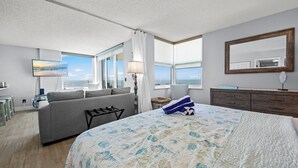 A hotel room with a large bed, a sofa, a desk, and a view of the sea. - Ocean Views From Every Window | Condo 206C at Estero Beach & Tennis Club + 2 Bikes, Beach Gear. 6-7night stays (Fort Myers Beach)