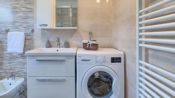 A modern bathroom with a sink, mirror, and a built-in washing machine. - Apartment Meden by Interhome (Pula/Galižana)