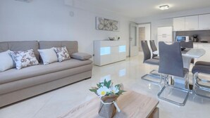 Un salon moderne comprenant un canapé, une table basse et un coin repas avec des chaises et une table.