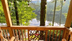A wooden deck with a bench overlooking a lake surrounded by trees.