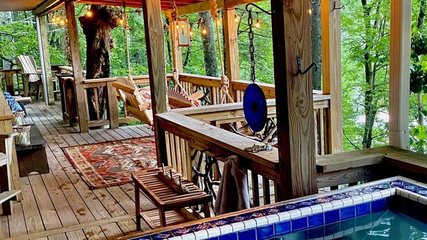A wooden deck with a pool, surrounded by trees.