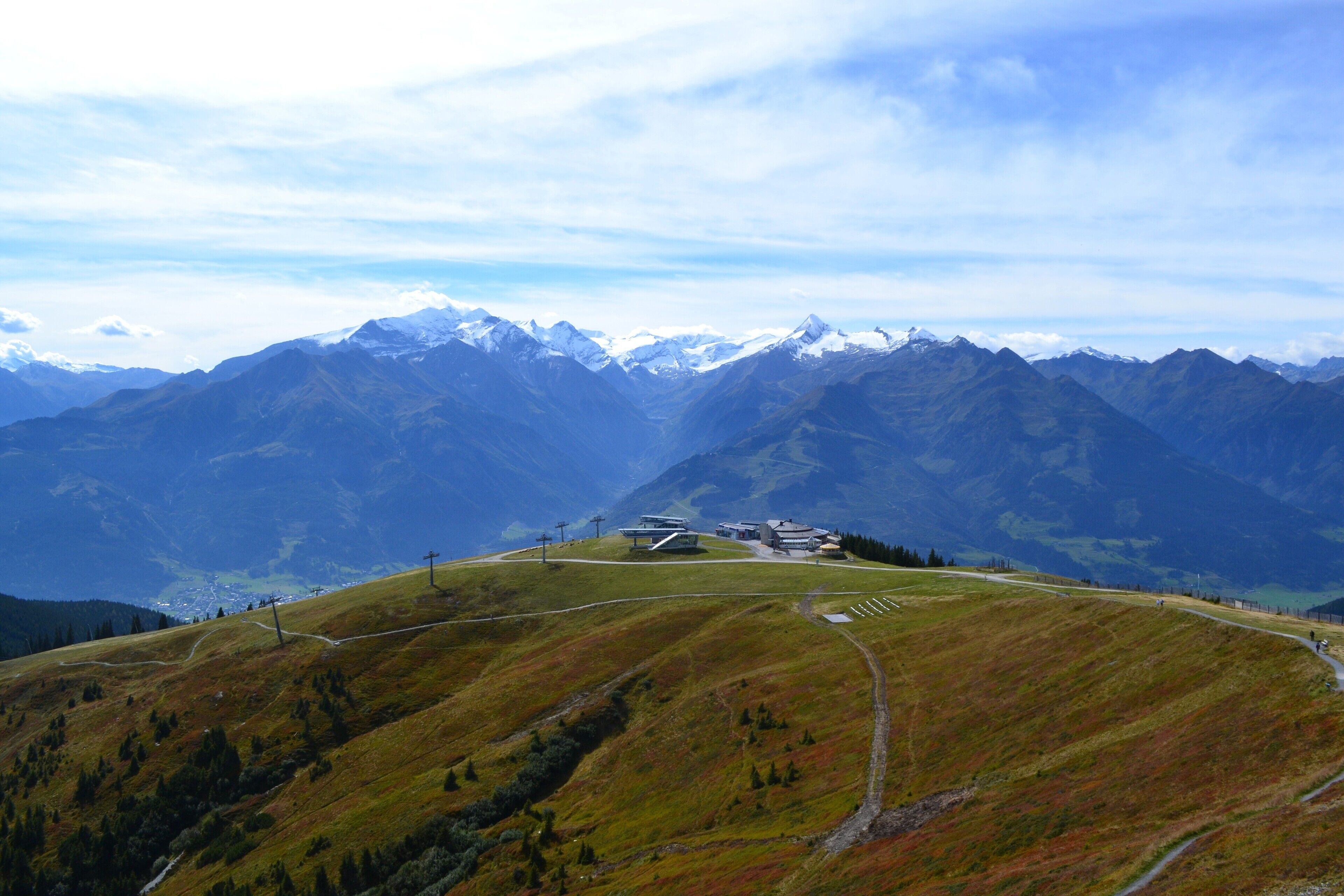 A mountainous landscape with a clear sky, a winding road, and a building with a modern design.