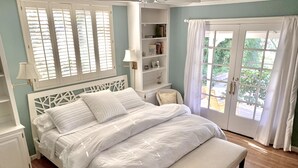 A neatly arranged bedroom with a bed, bedside tables, a lamp, and a window with curtains. - Hidden Country Gem with Pond | Free Early In & Late Out | Pet Friendly! (Nevada City)