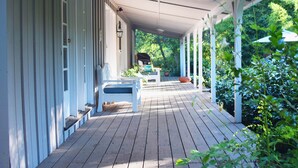 A covered porch with a wooden floor, white railings, and a bench. - Hidden Country Gem with Pond | Free Early In & Late Out | Pet Friendly! (Nevada City)