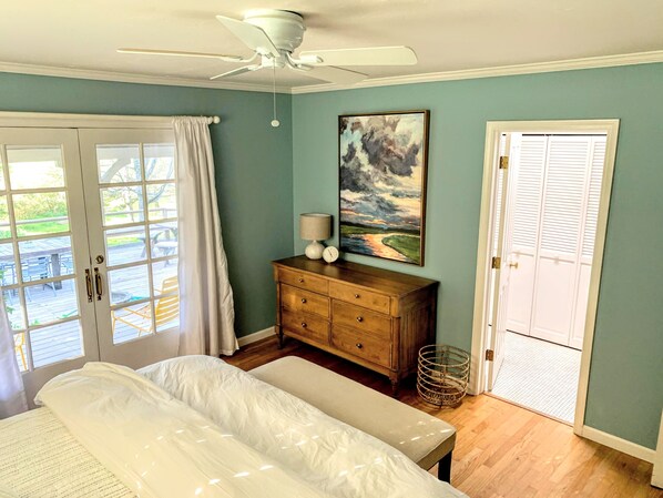 A bedroom with a bed, a dresser, a ceiling fan, a painting, and a door leading to an outdoor area. - Hidden Country Gem with Pond | Free Early In & Late Out | Pet Friendly! (Nevada City)
