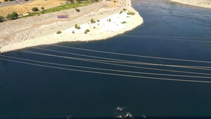 An aerial view of a river with a bridge and a town on the opposite bank.